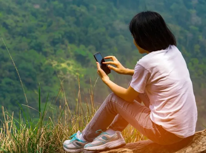 Girl reading an ebook on a hillside
